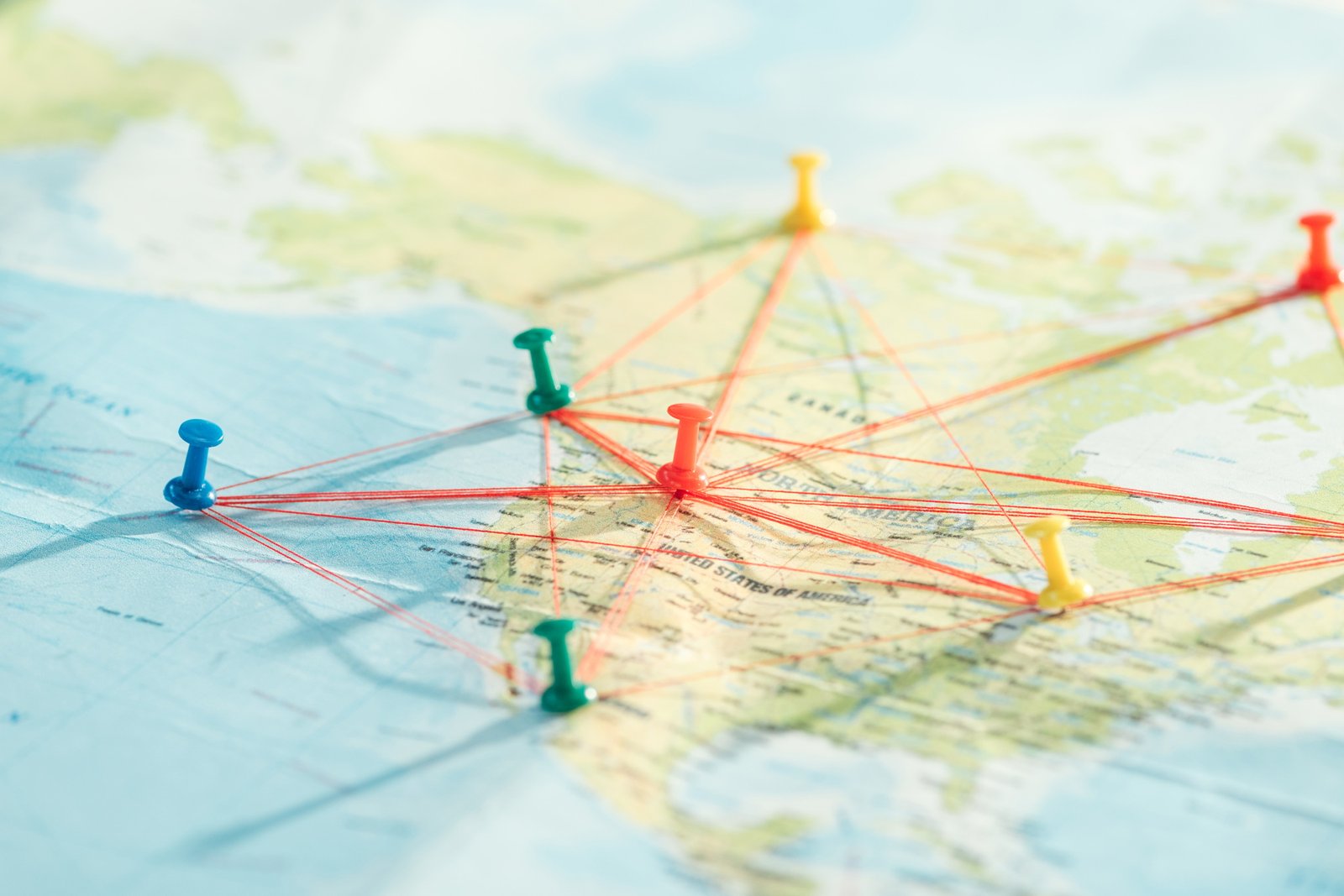 Selective focus of push pins and strings on world map